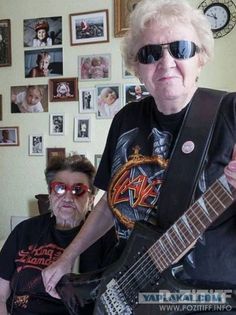 an older woman with sunglasses on holding a guitar in front of a man sitting down