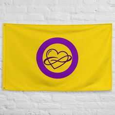 a yellow and purple flag hanging on a white brick wall with a heart in the center