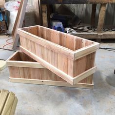 two wooden boxes sitting on top of a floor next to a pile of wood planks