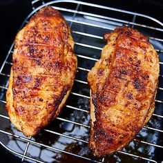 two pieces of meat cooking on a grill