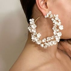 a close up of a person wearing large white flowers on their hoops and earrings