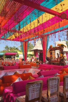 an outdoor event with bright colored linens and decorations on the ceiling, chairs and tables