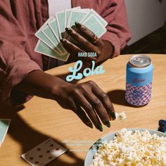 a person sitting at a table with popcorn and soda