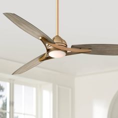 a ceiling fan that is hanging in a room with white walls and windows behind it