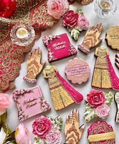 decorated cookies are arranged on a table with pink flowers and other decorative items in the background