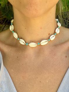 a woman wearing a necklace with seashells on it