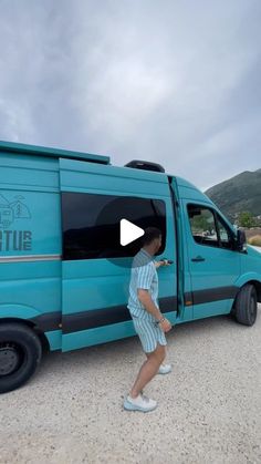 a man walking in front of a blue van