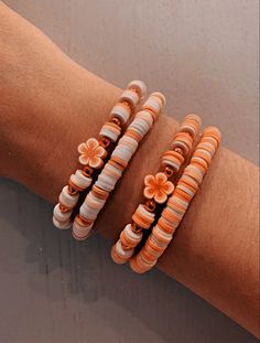 two bracelets with flowers on them sitting on a person's arm