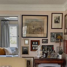 a living room filled with furniture and framed pictures on the wall next to a fire place