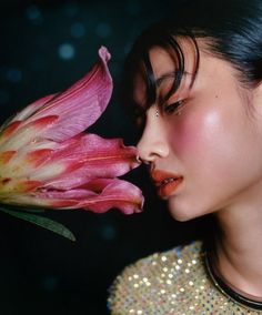 a woman is smelling a flower with her eyes closed