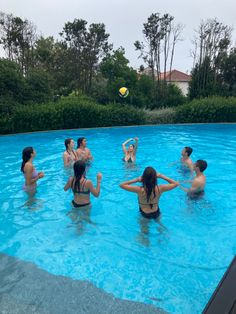 several people are in the pool playing volleyball