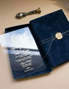 an open blue book with a wedding card in it and a key on the table