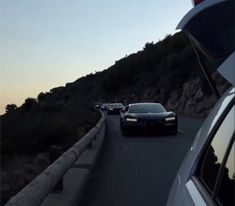 two cars are driving down the road in front of another car on the other side