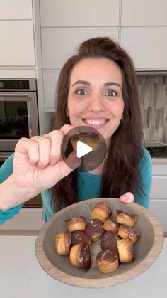 a woman is holding up a chocolate covered doughnut