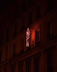 an illuminated sign on the side of a building in paris, france at night time