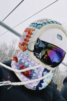 a person wearing a knitted hat with ski goggles attached to the brim