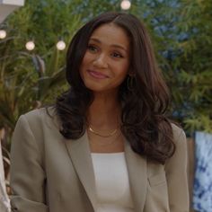 a woman in a tan blazer and white top