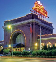 an old brick building with lights on it's roof and the words grand central station lit up at night