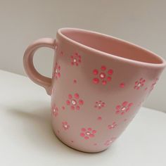 a pink coffee cup sitting on top of a white table