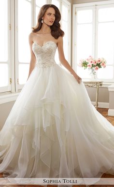 a woman in a wedding dress standing by a window