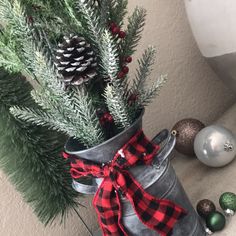 a christmas tree in a metal bucket with a red and black plaid ribbon tied around it