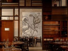 an empty restaurant with tables and chairs in front of a large painting on the wall