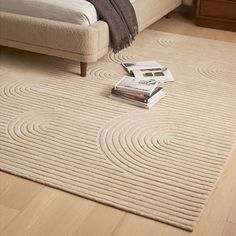 a bed sitting on top of a wooden floor next to a white rug covered in magazines