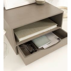 an open drawer with papers and other items in it on a white countertop next to a framed photograph