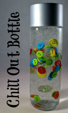 a bottle filled with lots of buttons sitting on top of a white table next to a silver lid