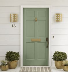 a green door with two planters on either side