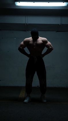 a man standing in the dark with his hands on his hips