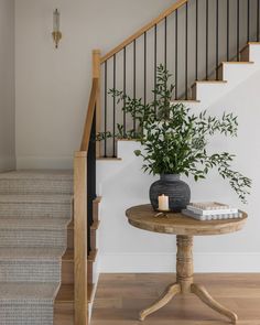 a table with a potted plant on it next to a stair case and railing