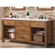 a bathroom vanity with two sinks and baskets under the faucet in front of a stone wall