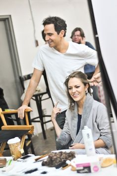 a man and woman are sitting at a table with other people in the back ground