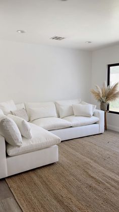 a large white couch sitting in the middle of a living room next to a window