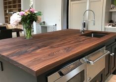 a kitchen counter top made out of wood and stainless steel with flowers in vase on it