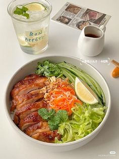 a white bowl filled with meat and veggies next to a cup of tea