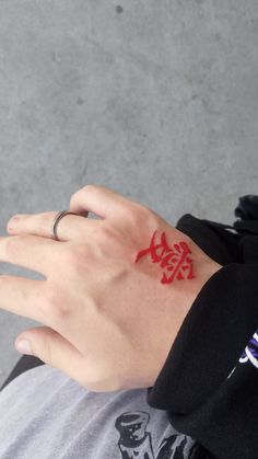 a person's hand with a red tattoo on it