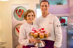 a man and woman holding a plate with cupcakes on it