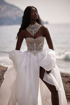 a woman in a white dress standing on the beach