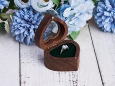 a wooden box with a ring inside and flowers in the background