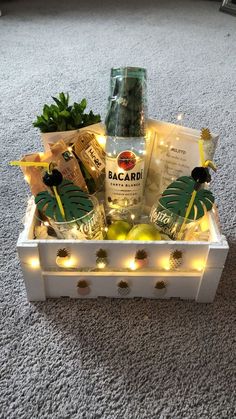 a white box filled with drinks and snacks on top of a carpeted floor next to a bottle of booze