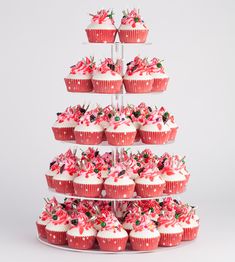 a three tiered cupcake display with pink frosting and sprinkles