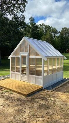 a small white house sitting on top of a wooden platform in the middle of a field