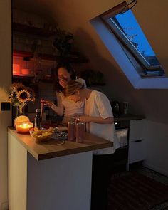 a man and woman standing in a kitchen next to a counter with food on it