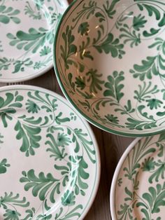 four green and white plates sitting on top of a wooden table next to each other