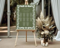 a wedding seating chart on an easel with flowers and candles in front of it