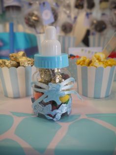 a bottle filled with candy sitting on top of a table next to cupcakes