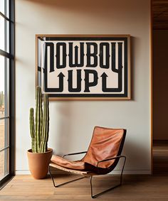 a chair sitting in front of a window next to a potted cactus and a sign that says cowboy up