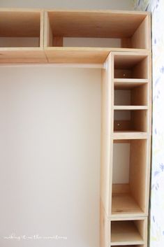 an empty closet is shown with shelves and drawers on the bottom shelf, in front of a floral wallpapered background